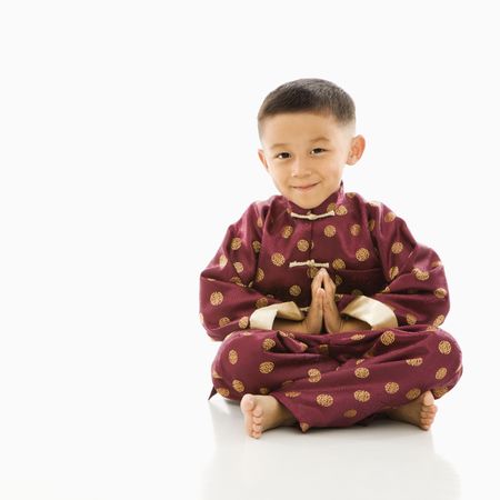 Asian boy sitting meditating against white background in traditional  attire.の写真素材