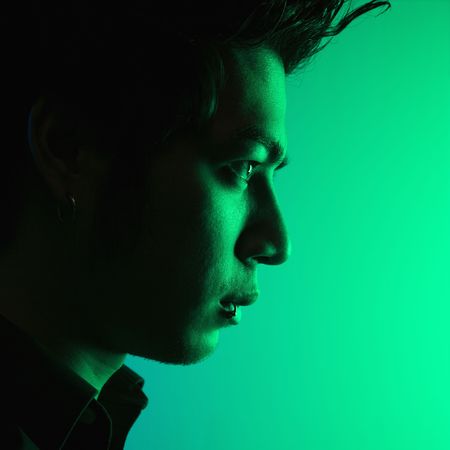 Close up side view of attractive young Asian man tinted green.