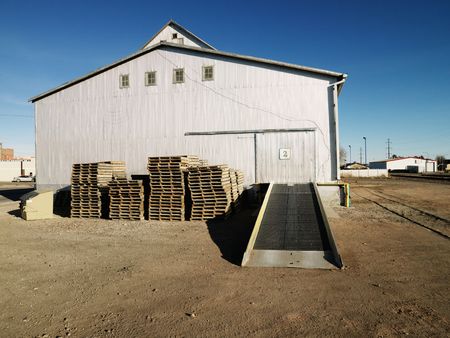 Storage warehouse with ramp and palettes in rural setting.