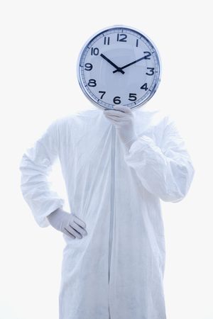 Man in biohazard suit holding clock in front of face standing against white background.の写真素材