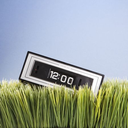 Studio shot of retro alarm clock placed in grass.