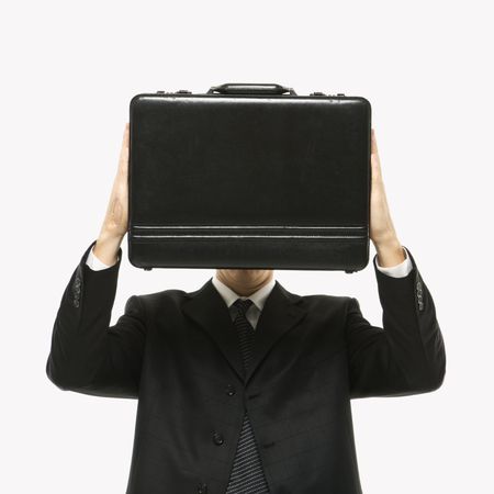 Caucasian man wearing suit and holding briefcase in front of face.の写真素材