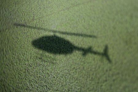 Shadow of helicopter above green marsh with abundant foliage.の写真素材