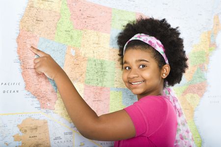 African American girl pointing to map of United States and smiling at viewer.の写真素材