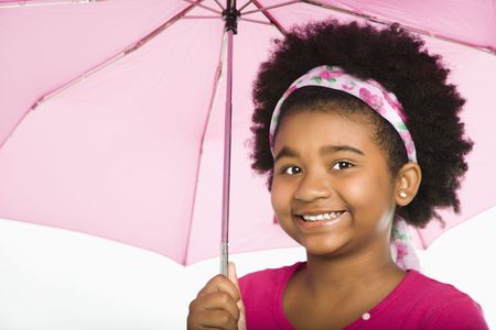 African American girl holding pink umbrella smiling at viewer.の写真素材