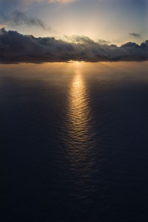 Aerial of sun setting over Pacific ocean with clouds.の写真素材