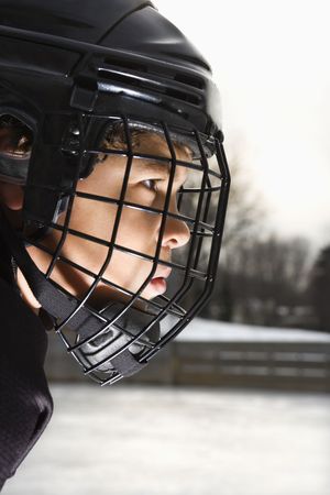 Ice hockey player boy in uniform and cage helmet concentrating.の写真素材