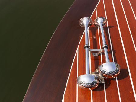 Detail of dual chrome trumpet horns on wooden boat floating in water.の写真素材