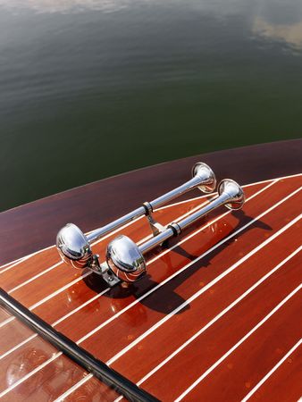 Detail of dual chrome trumpet horn on wooden boat floating in water.の写真素材