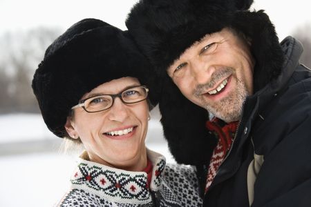 Portrait of happy Caucasian middle aged man and woman in winter clothing and black hats looking at viewer smiling.の写真素材