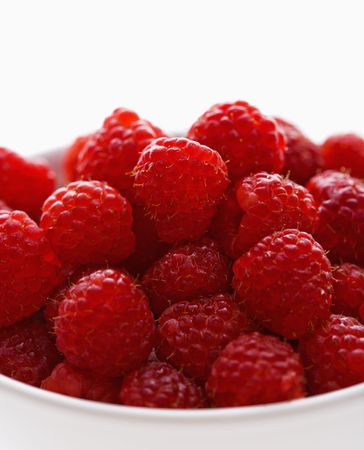 Bowl of raspberries against white background.