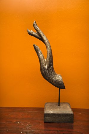 Carved hand sculpture from Thailand against orange wall.の写真素材