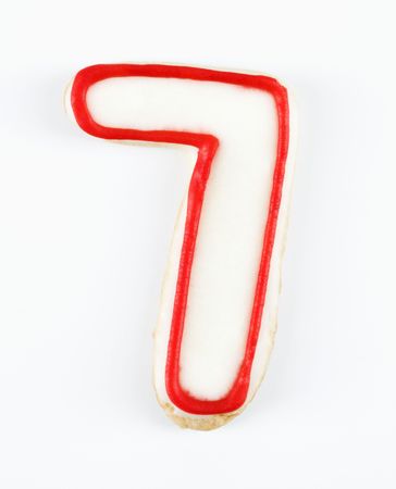 Sugar cookie in the shape of a number seven outlined in red icing.