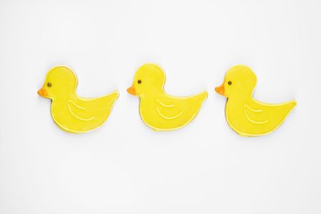 Three sugar cookies in shape of ducks with decorative icing.