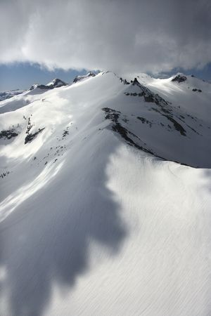 Aerial of snow covered mountain with clouds in Crystal Range, California, USA.