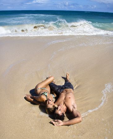 Attractive couple lying on beach smiling and laughing in Maui, Hawaii.の写真素材