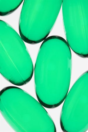 Close up of green capsule pills against white background.の写真素材