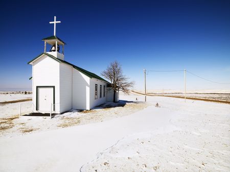 White small church with snow covered ground in foreground.の写真素材