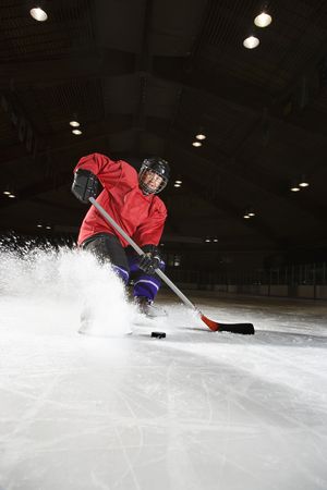 Caucasian woman hockey player sliding kicking up ice.の写真素材