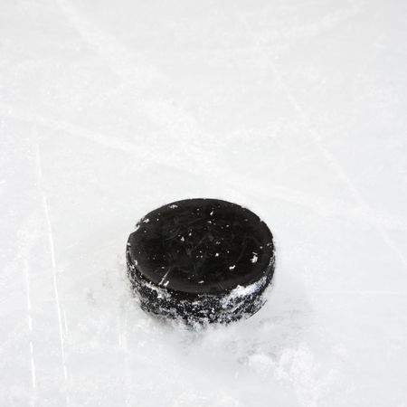 Black hockey puck on ice rink.