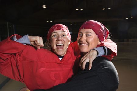 Women hockey players excited and posing with helmets off on ice rink.の写真素材