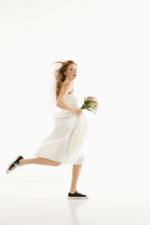 Caucasian bride running and holding bouquet.の写真素材