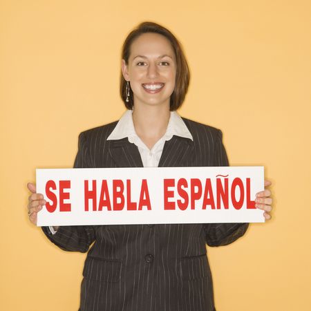 Caucasian businesswoman smiling holding sign reading "se habla espanol."の写真素材