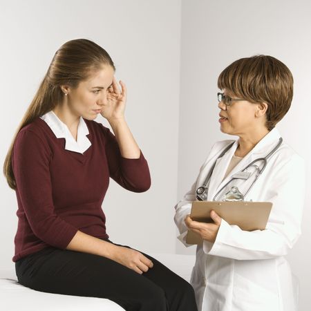 African American middle-aged female doctor listening to  Caucasian mid-adult female patient explain her symptoms.の写真素材