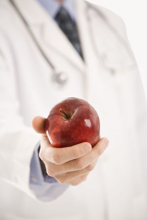 Caucasian mid adult male physician holding apple.の写真素材