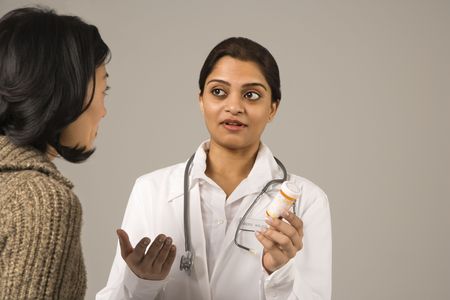 Indian woman doctor explaining medication to Asian woman patient.の写真素材