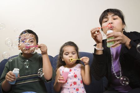 Family sitting together blowing soap bubbles.の写真素材