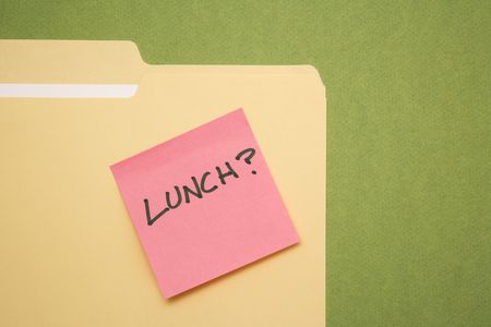 Folder with pink sticky note reading lunch on a green background.の写真素材