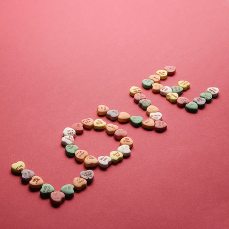 Colorful candy hearts with sayings on them arranged to spell the word love.の写真素材