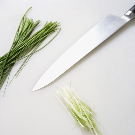 Fresh chives with kitchen knife resting on countertop.の写真素材