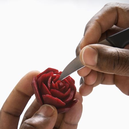 African-American male hands carving a red beet into a rose.の写真素材