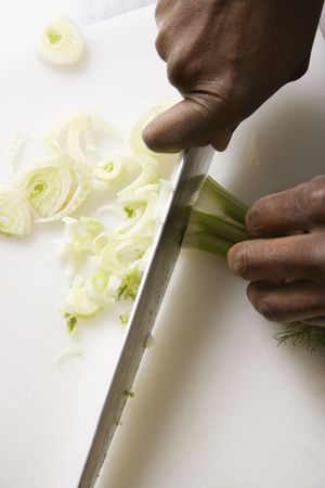 African-American male hands using large kitchen knife to chop fennel.の写真素材