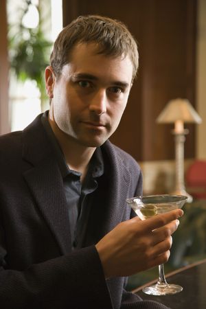 Mid adult Caucasian man holding martini and looking at viewer.の写真素材