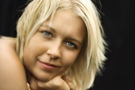 Caucasian young adult  woman resting chin on hands and smiling at viewer.の写真素材