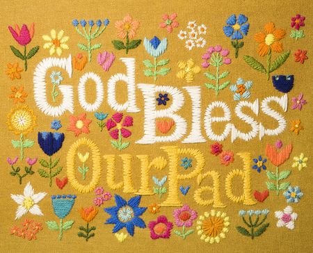 Vintage needlepoint wall hanging of colorful flowers surrounding the phrase God Bless Our Pad.の写真素材