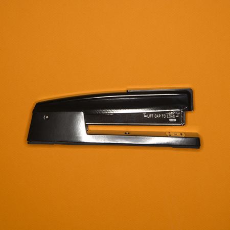 Black stapler on orange background.の写真素材