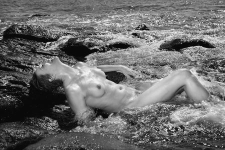 Mid adult nude Caucasian woman lying in water at Maui, Hawaii beach.の写真素材