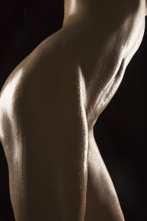 Side view of thighs and stomach of nude Hispanic mid adult woman glistening with body oil.の写真素材