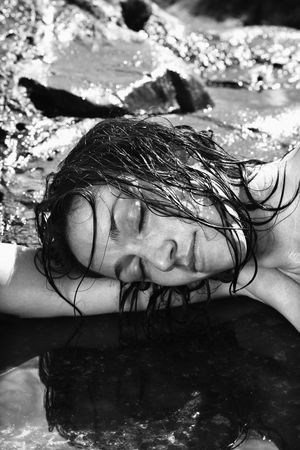 Close up of  Caucasian mid adult woman lying in water at Maui coast with head resting on arm.の写真素材