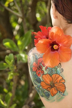 Back view of tattooed Caucasian woman with Hibiscus flower over her shoulder in Maui, Hawaii, USA.の写真素材