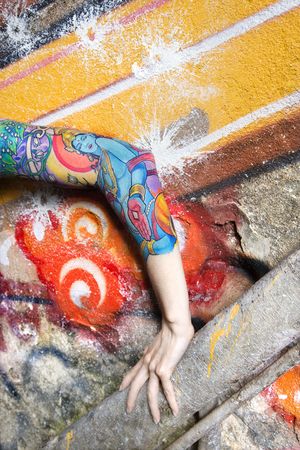 Tattooed Caucasian woman's arm against graffiti covered wall.の写真素材