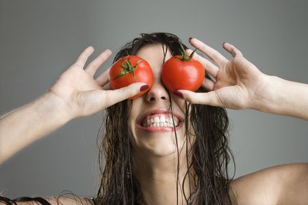 Caucasian woman with tomatoes covering her eyes.の写真素材