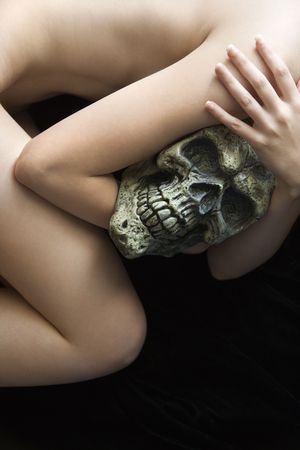  Caucasian young adult woman lying down holding human skull.の写真素材