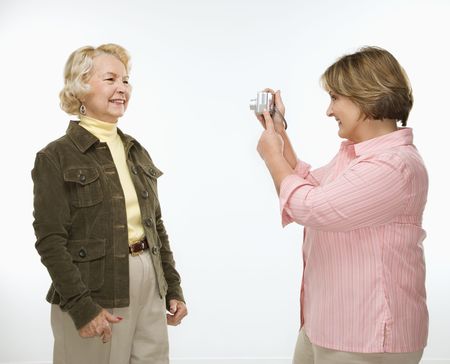 Caucasian middle aged woman taking photo with digital camera of senior woman.の写真素材