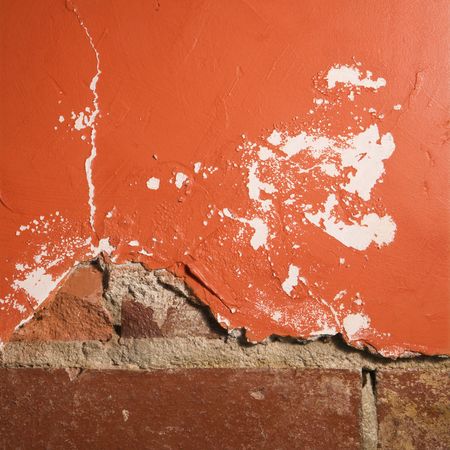 Red wall with cracking plaster and brick.