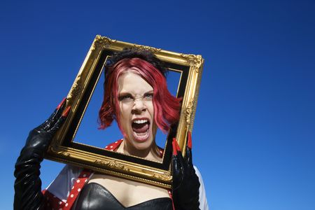 Young adult Caucasian female holding empty frame around head.の写真素材
